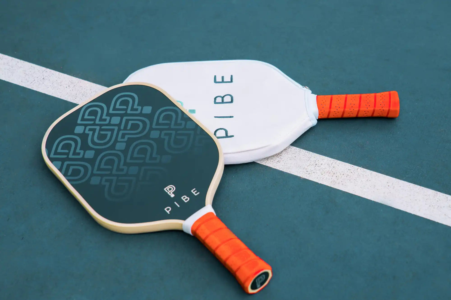 White pickleball paddle with orange grip handles and a geometric pattern design.